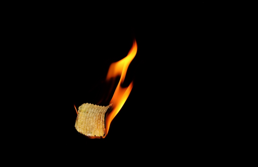 Burning Potato Chip Isolated in Black Background with Copy Space for Texts Writing in Horizontal Orientation.