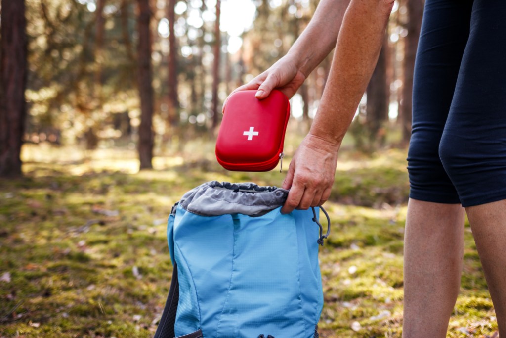 Woman taking out first aid kit from backpack