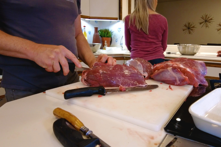 Mature Adult Male Cutting Venison Tenderloin and Steaks Grinding Meat into Burger Hunting in Western Colorado
