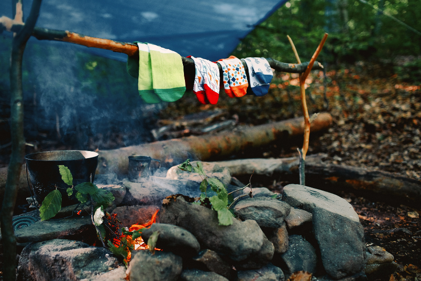 Drying wet socks on the bonfire during camping. Socks drying on fire. Active rest in forest.