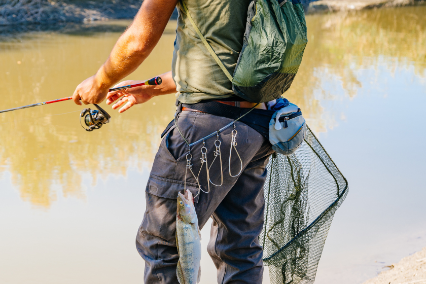 Fish hanging on Fisherman's belt with fishing rodFish hanging on Fisherman's belt with fishing rod