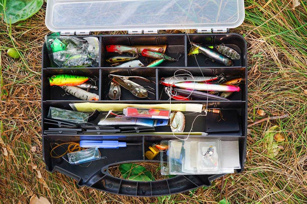 An open tackle box full of fishing lures on the ground.