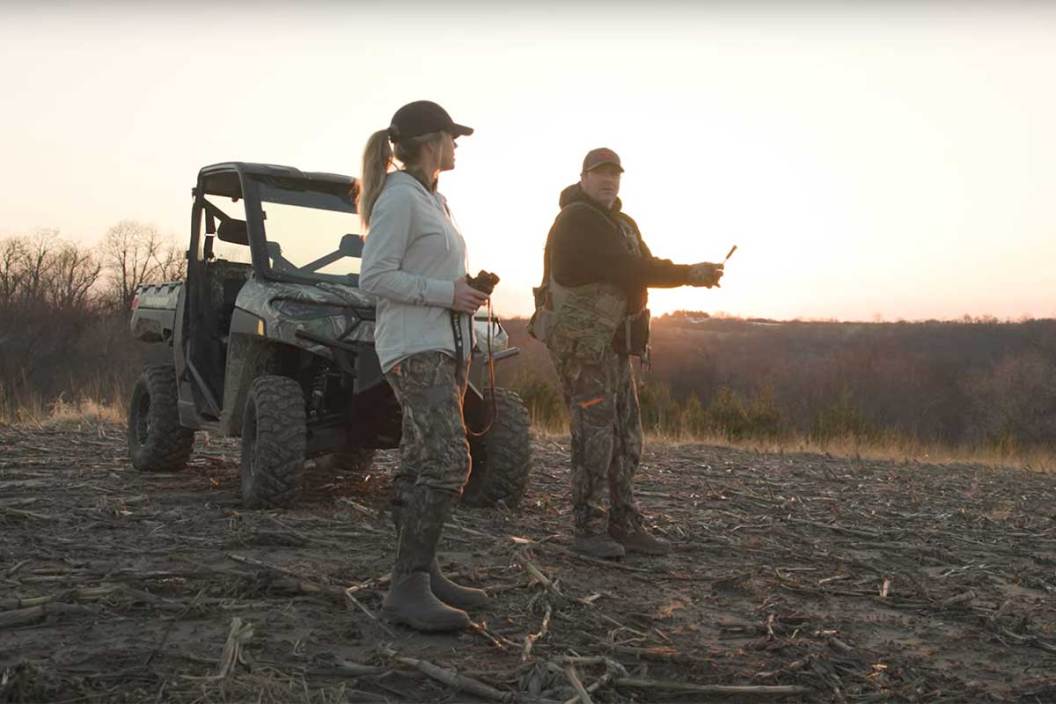 Two turkey hunters stand in front of a Polaris RANGER Kinetic.