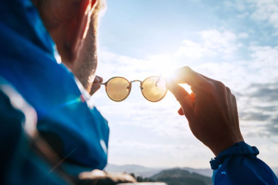 man holding sunglasses up to his face toward the sun