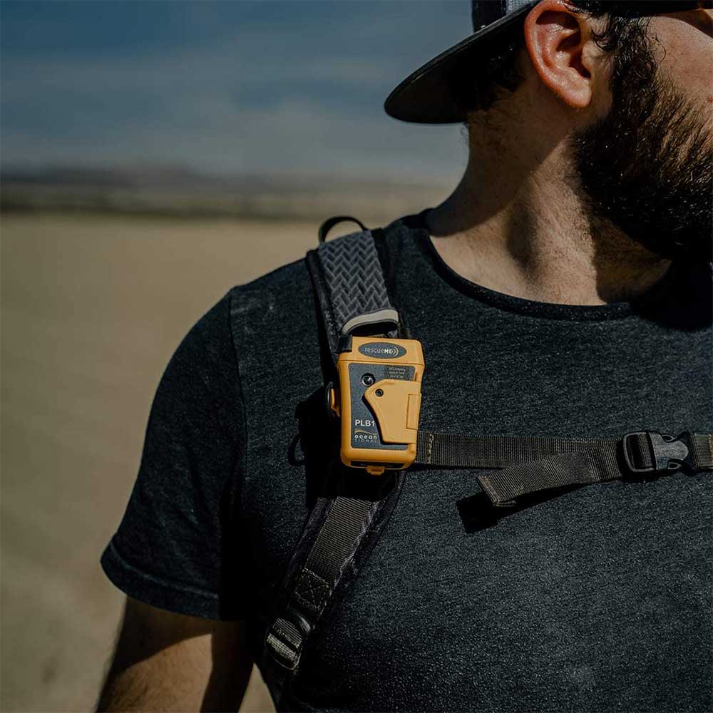 Personal Locator Beacon worn on a hiker's backpack strap.