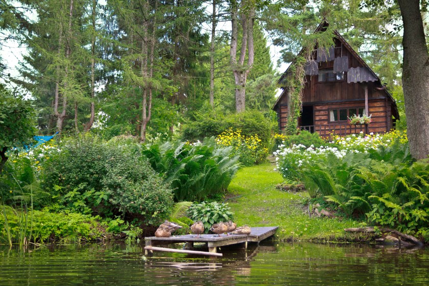 Summer scene with small log cabin at the river Krutynia, Masuria, Poland