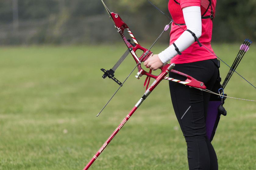Portrait of female athlete practicing archery in stadium.