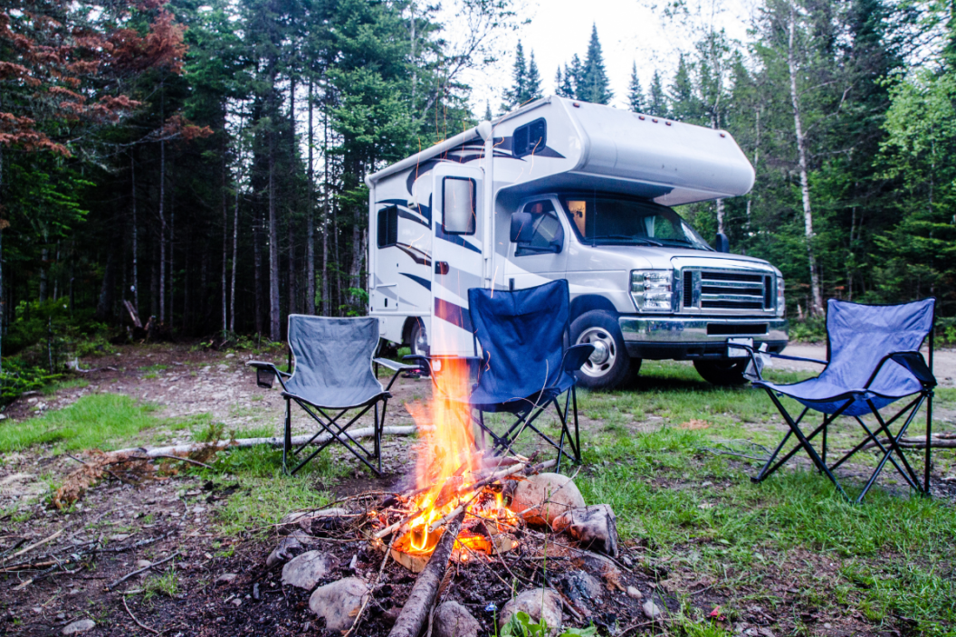 Campfire and motor home in background during summer day