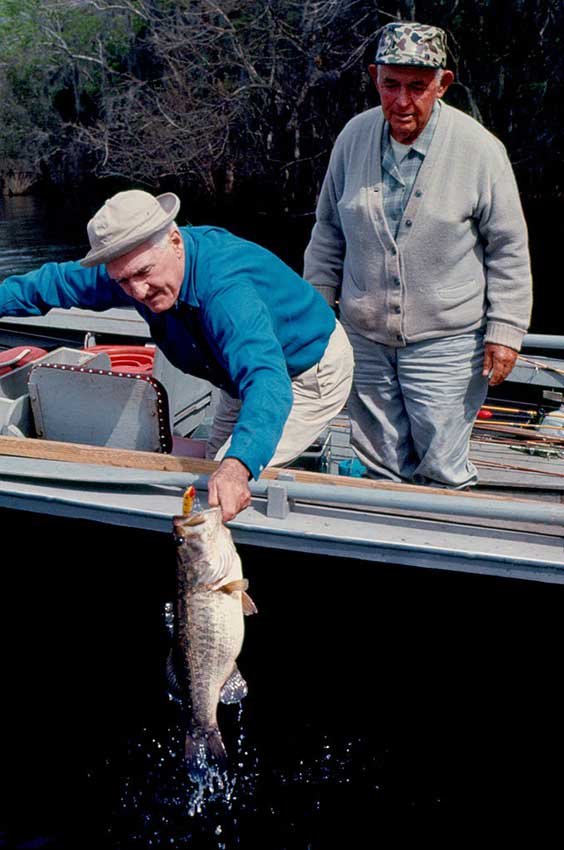 Florida anglers land a largemouth bass boatside.