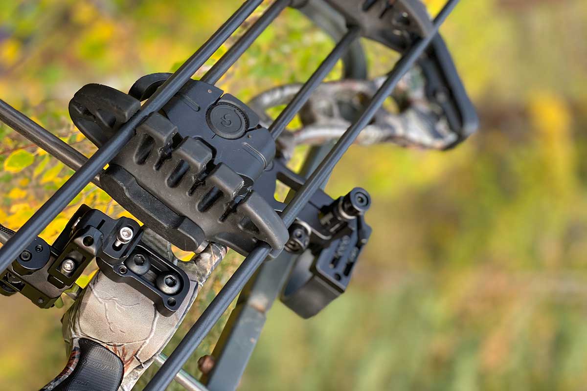 A hunting bow is shown close up with a forest background.