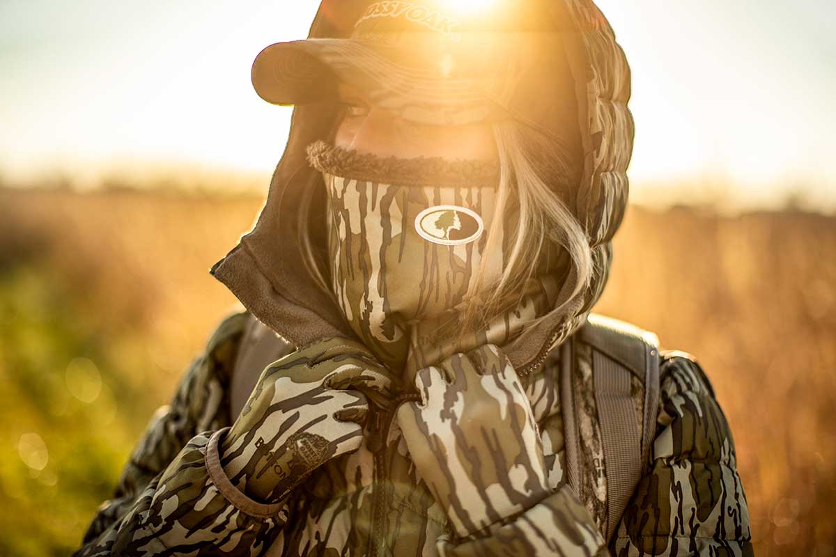 Female hunter in Mossy Oak camo stands in a field