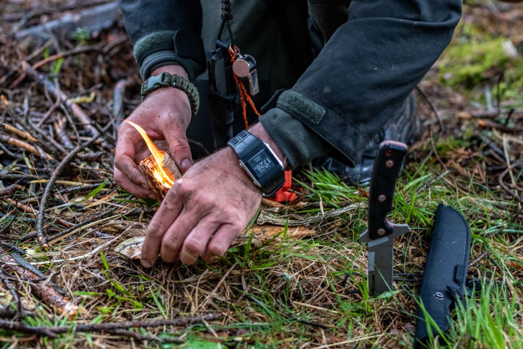 Close-up of man's hands igniting fire in forest.