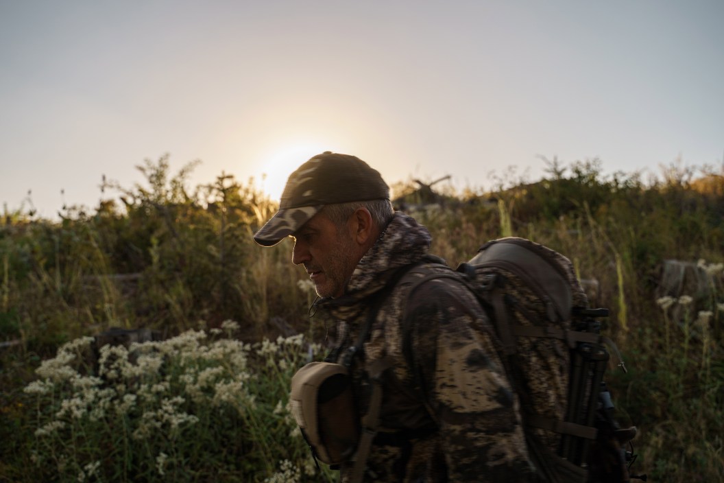 Middle aged Caucasian, male hunter hikes in a field of wildflowers at sunrise, searching for elk in the Pacific Northwest mountains.