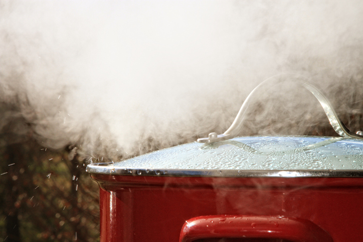A pot is releasing hot steam during boiling.
