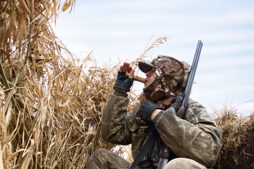 man using duck call while hunting