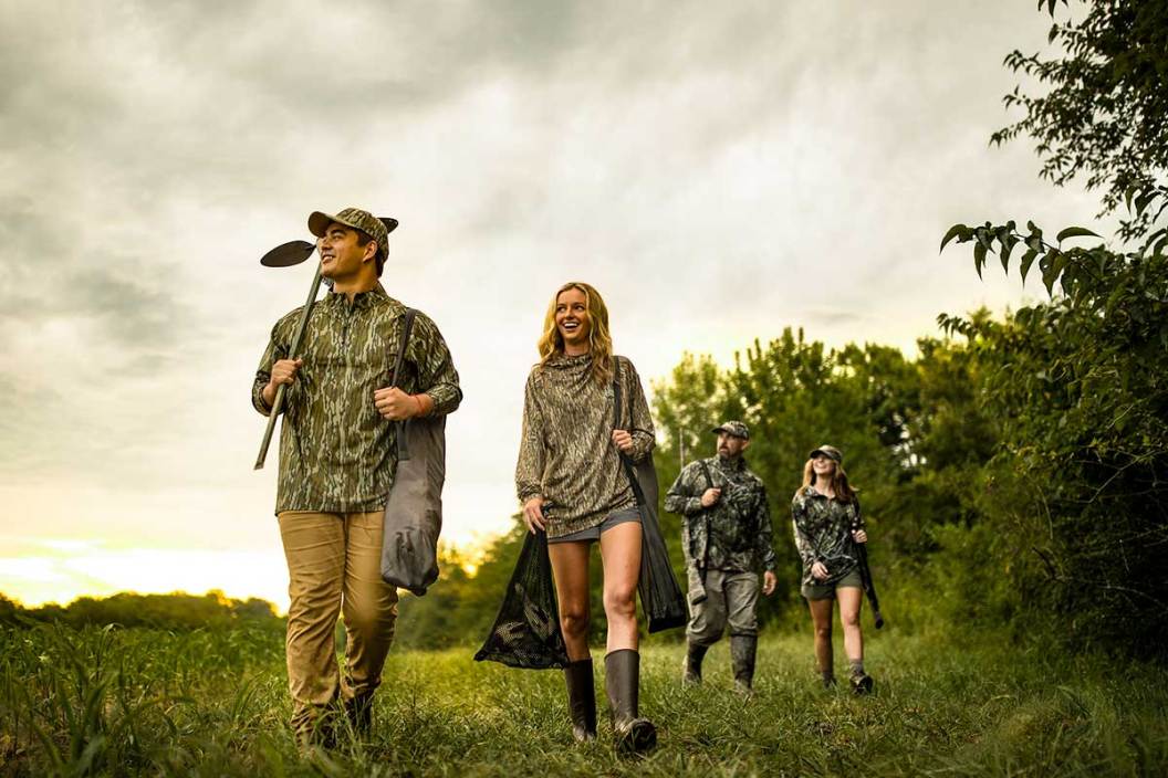 A group of bird hunters wearing camo head out to a field.