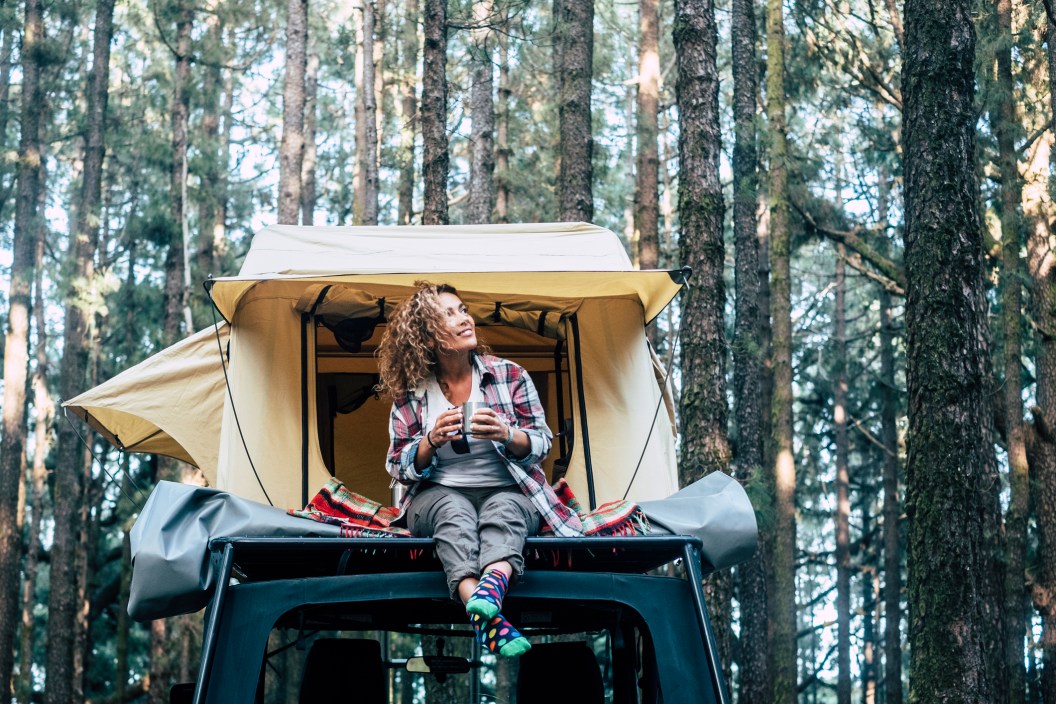 Woman happy car camping in the forest with a pop-up tent