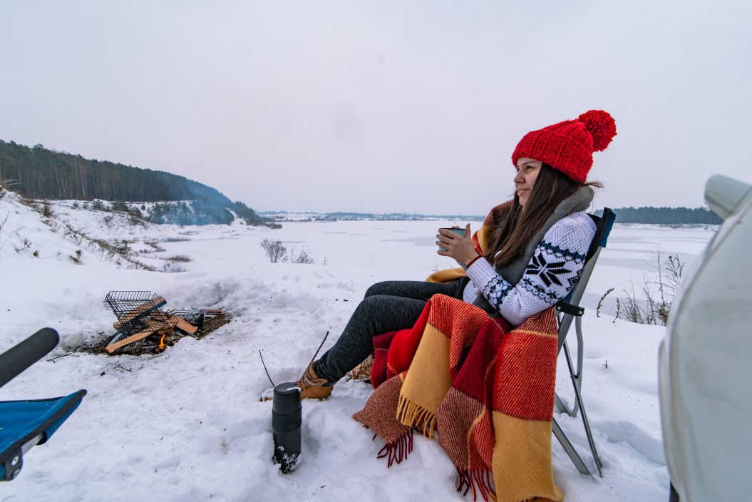 woman sitting in camp chair in winter staying warm