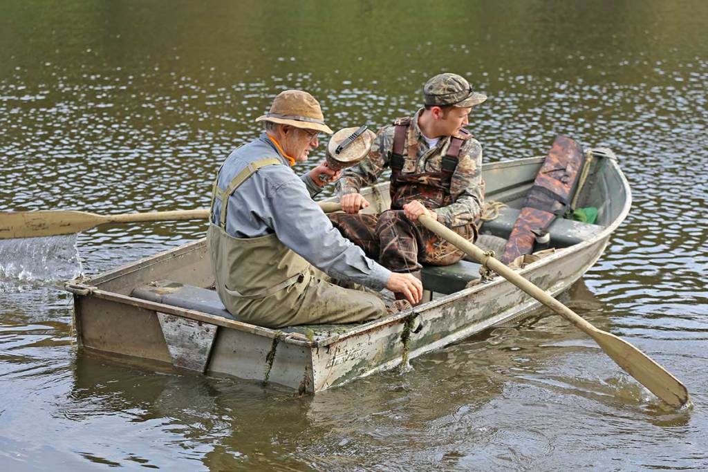 Two hunters in a canoe collect duck decoys from the water