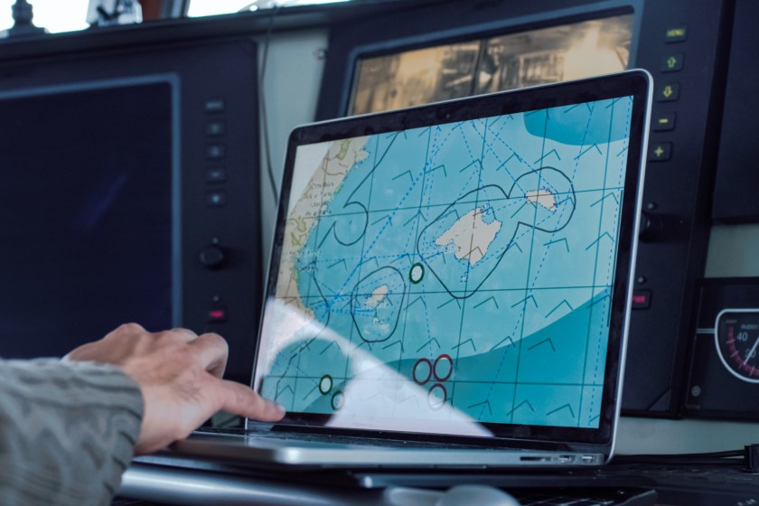 Captain of Commercial Fishing Ship Surrounded by Monitors and Screens Working with Sea Maps in his Cabin.