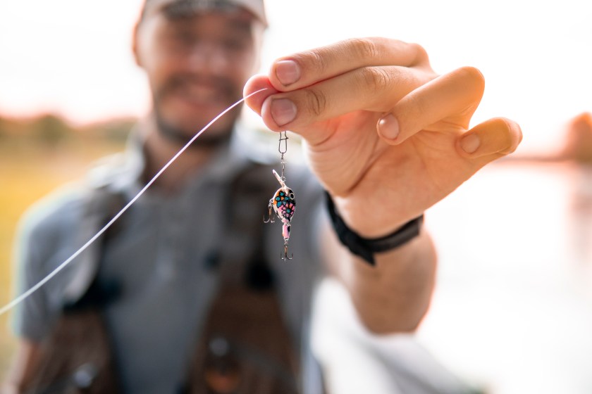 Picture of a caucasian guy, a fisherman showing a fishing lure
