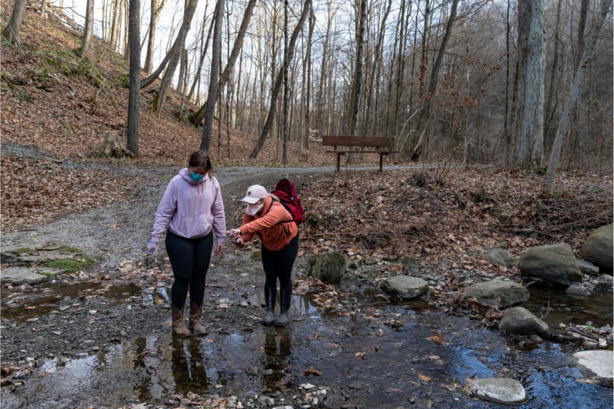Olivia Holley, 22, and Taylor Gulish, 22, collect water samples from Leslie Run creek on February 25, 2023 in East Palestine, Ohio.