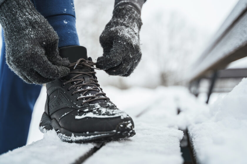 Jogger man is lacing his boots during his winter workout in a city park