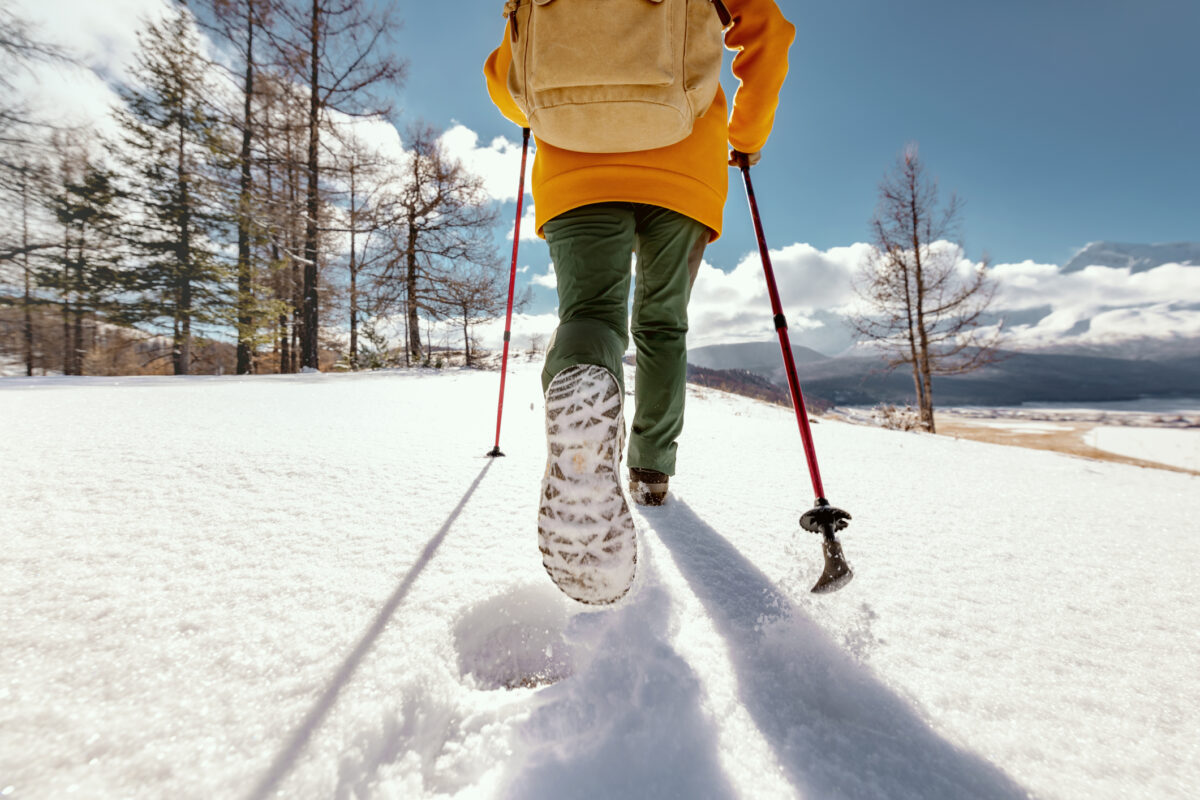 Active girl is walking in deep snow with hiking poles