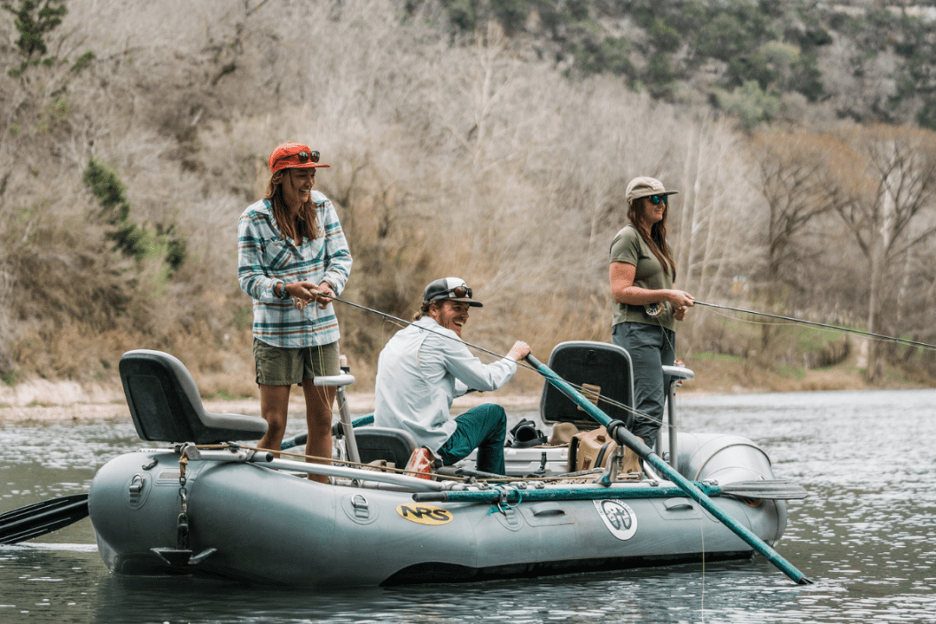 A group of people fishing in a river wearing Duck Camp apparel.