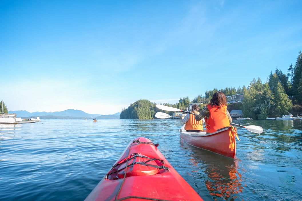 Mature mother and teen daughter enjoy morning kayaking and canoeing in rural Bamfield, British Columbia, Canada.