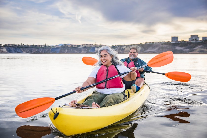 A couple kayaking on a flat river.
