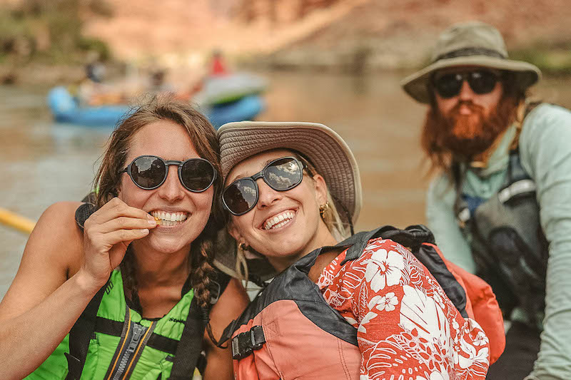 Three people wearing Ombraz armless sunglasses while rafting on a lake.