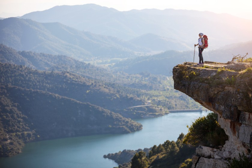 Female hiker standing on cliff and enjoying valley view