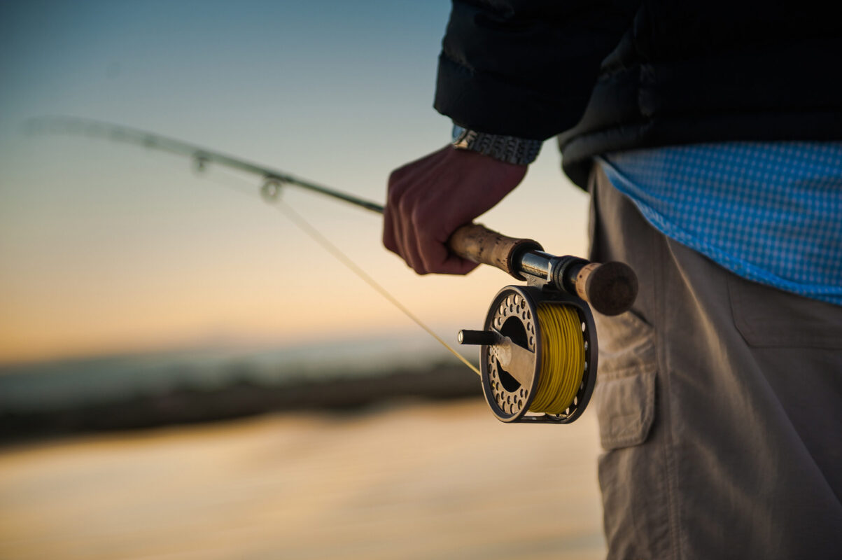 Sunrise over the marsh with man holding a fly rod and reel