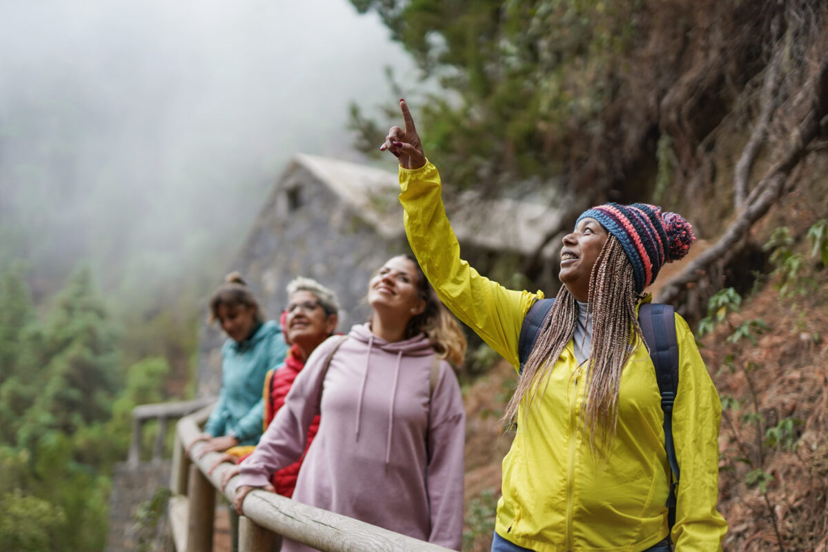 Multiracial female friends enjoy trekking day in the forest