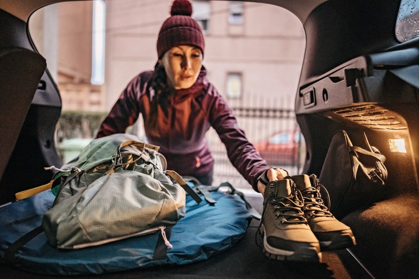 Woman packing her car with hiking equipment and preparing for new adventure