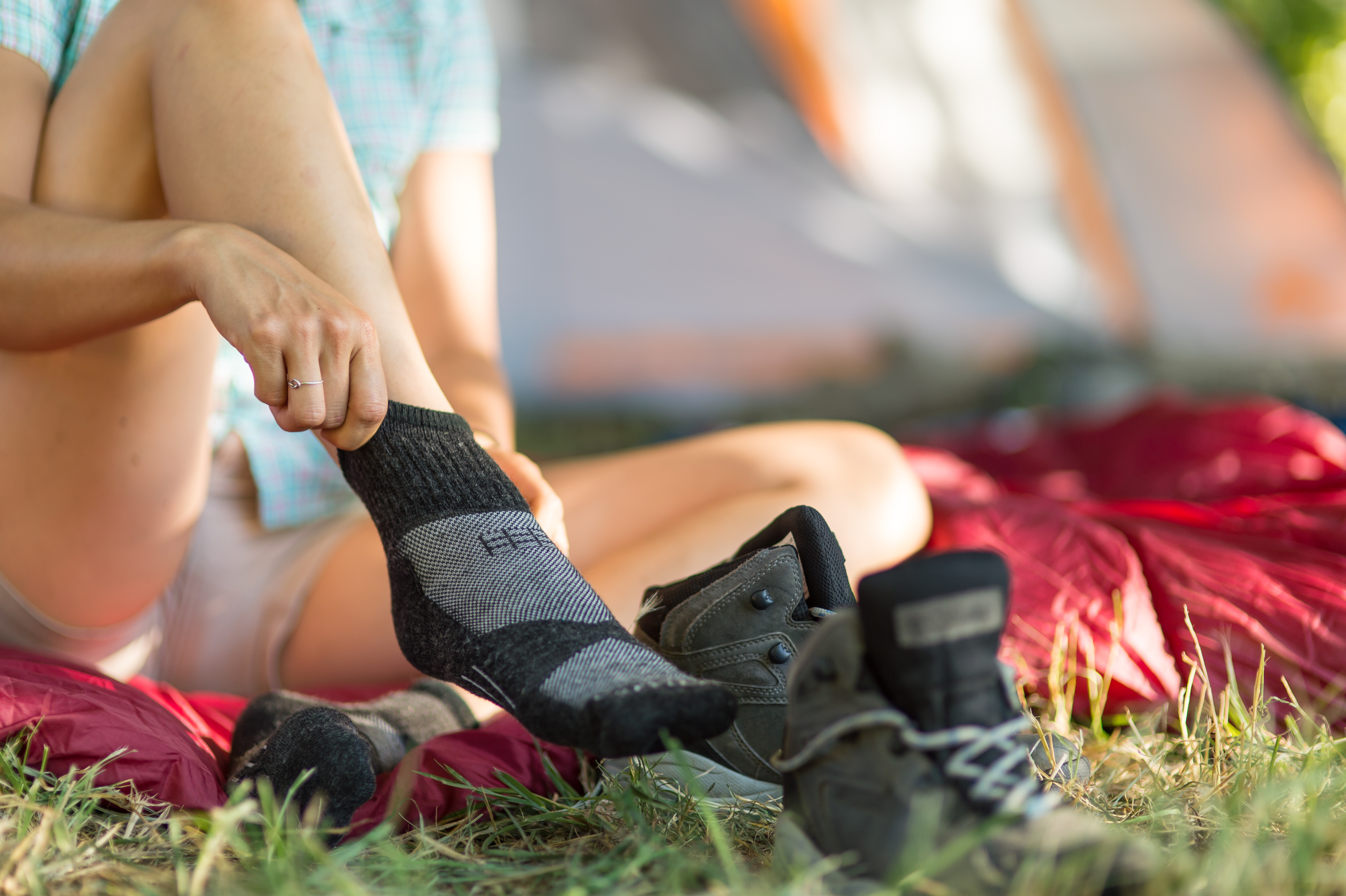 Young Hawaiian woman tying shoe outside tent