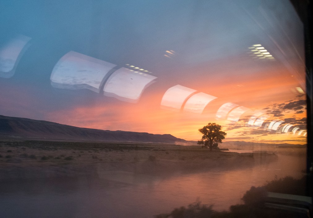 Sunrise in eastern Colorado, seen from the lounge car of the Amtrak train California Zephyr. Windows in the ceiling of a lounge car are reflected in a main window of the car.