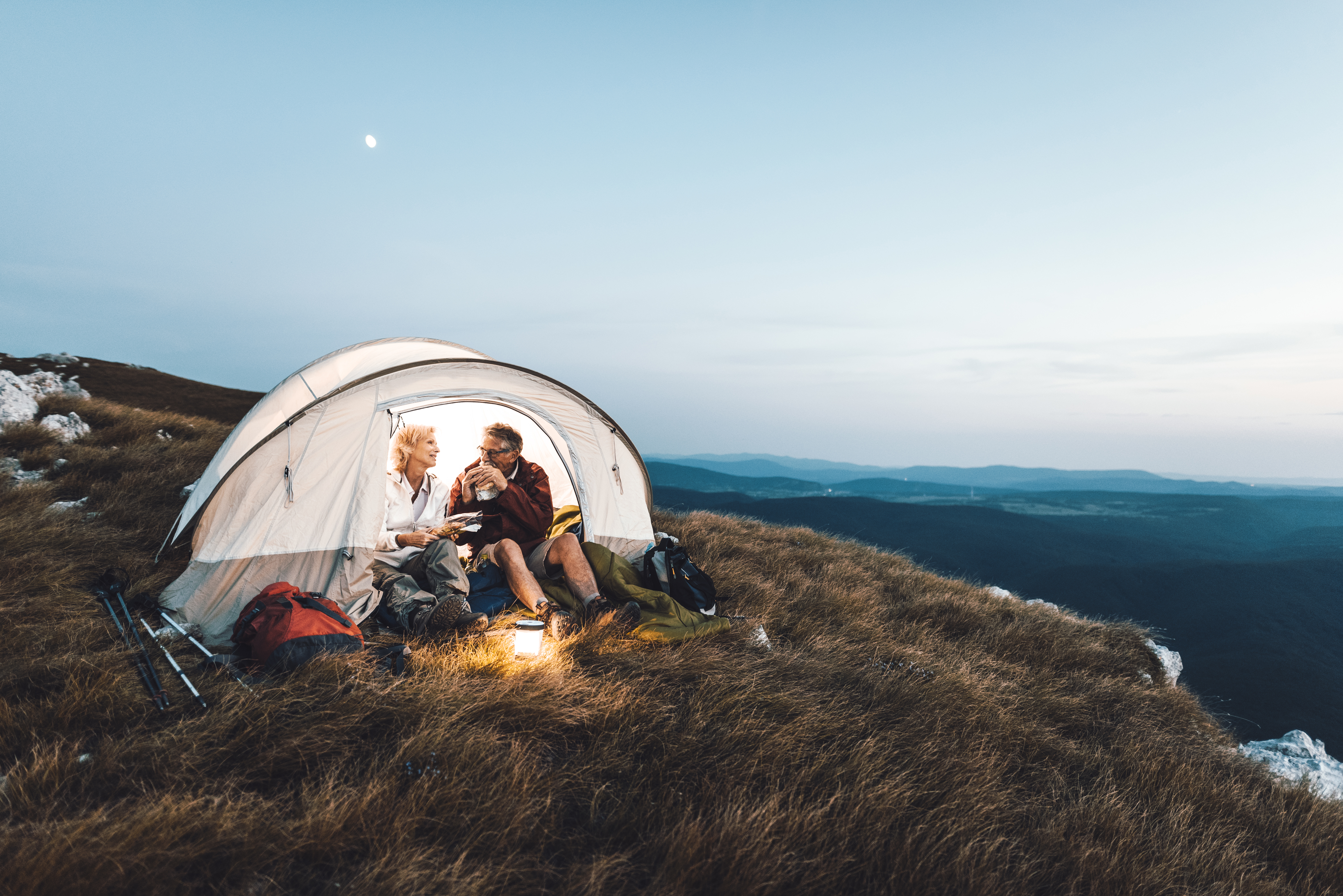 Senior couple camping in the mountains and eating a snack