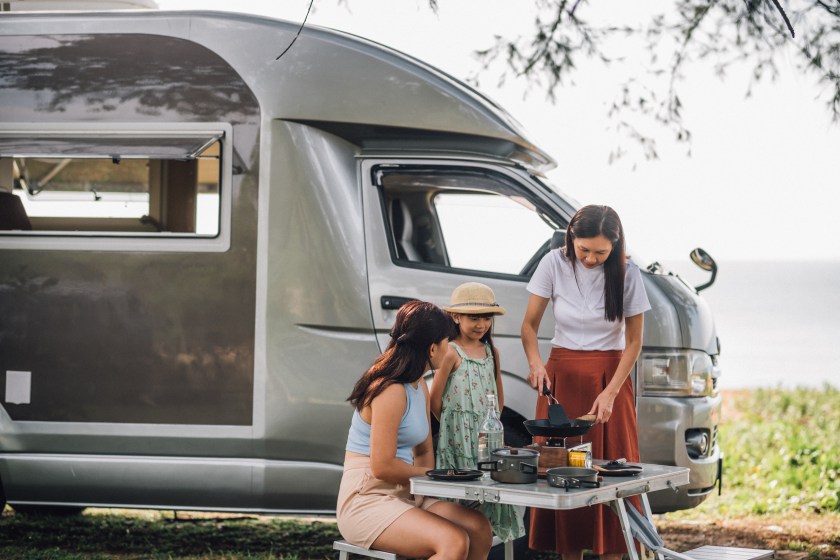 Asian Chinese Woman teaching her daughter cooking food while picnic by the camper trailer in nature. Camper van travel series