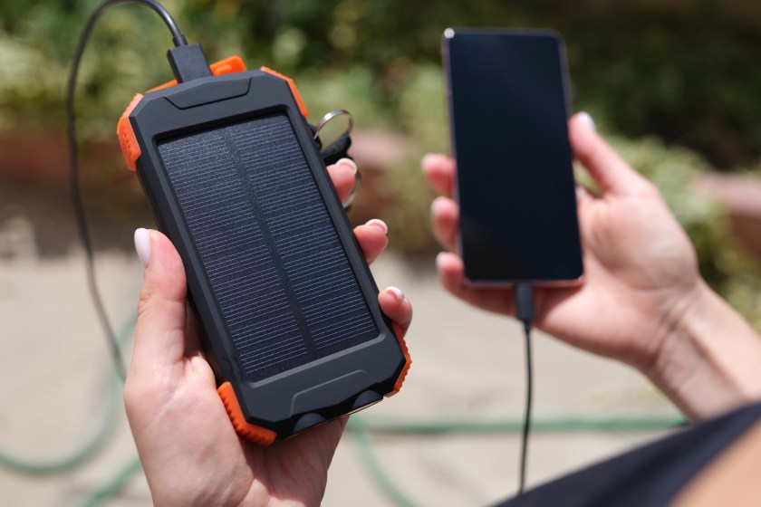 Female hand holding solar power bank and mobile phone closeup. Modern energy-saving devices concept