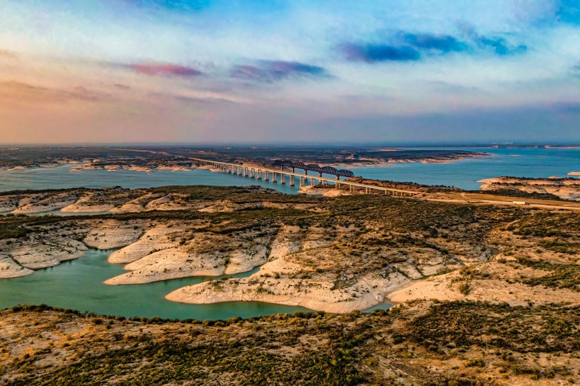 An aerial view of Amistad Reservoir with the Governor's Landing Bridge in Texas at sunset