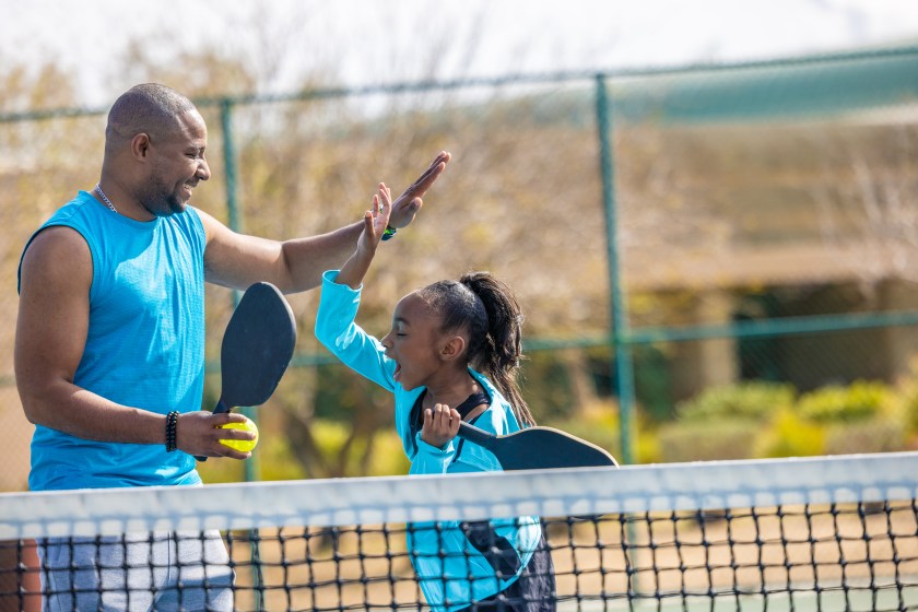 A young girl and her father playing Pickleball together