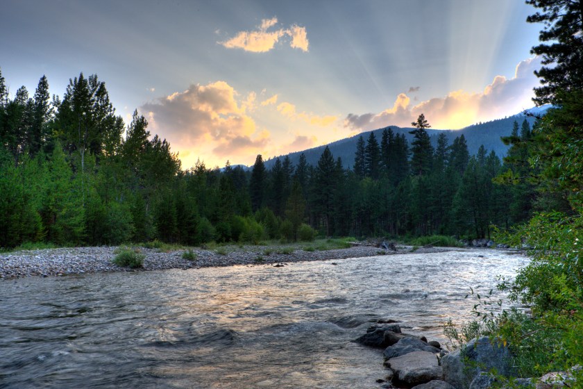 The rays of the setting sun illuminate the sky over the Bitteroot River. 