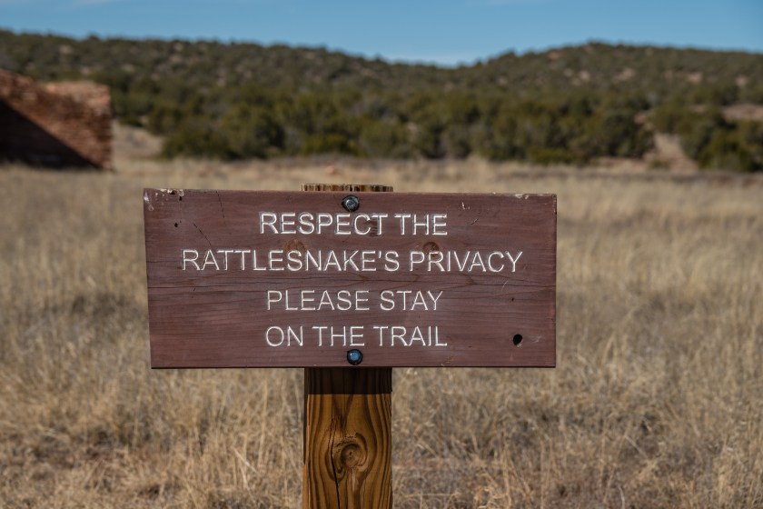 Sign on hiking trail reading "Respect the rattlesnake's privacy please stay on trail"