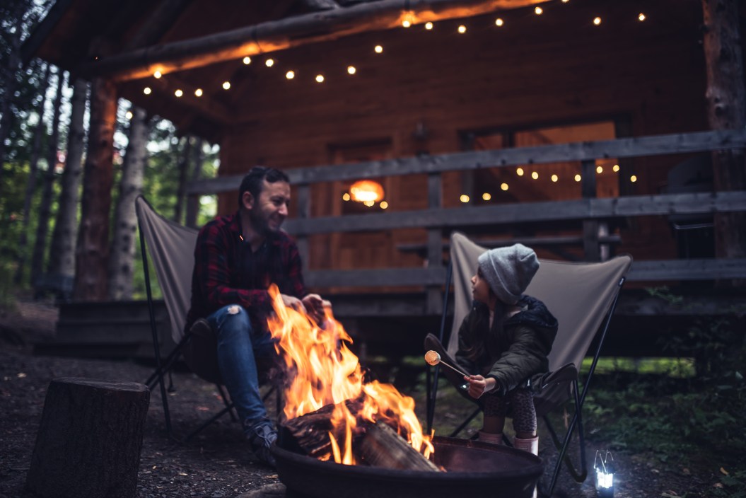 Father and daughter having fun by the campfire at their cabin in the woods
