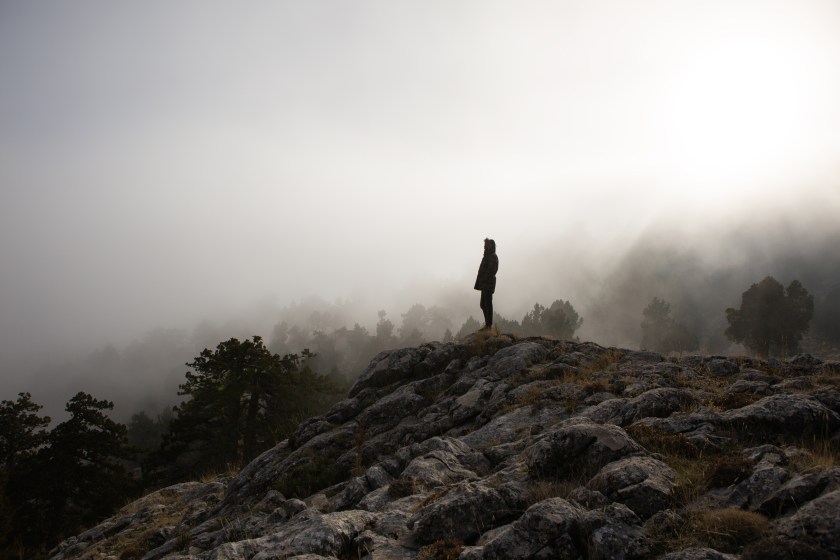 Landscape with traveler, foggy hills, amazing sky and sunlight in fall.