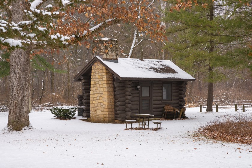 Cabin in the snow covered forest at White Pines Forest State Park, Illinois, USA.