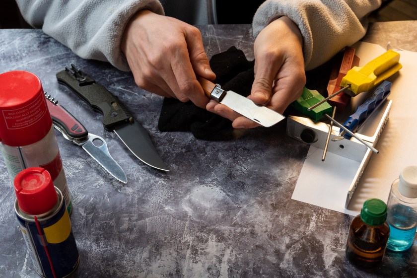 Sharpening and caring for a knife. Checking a knife for sharpness. The master holds a sharp knife in his hands. View from above.