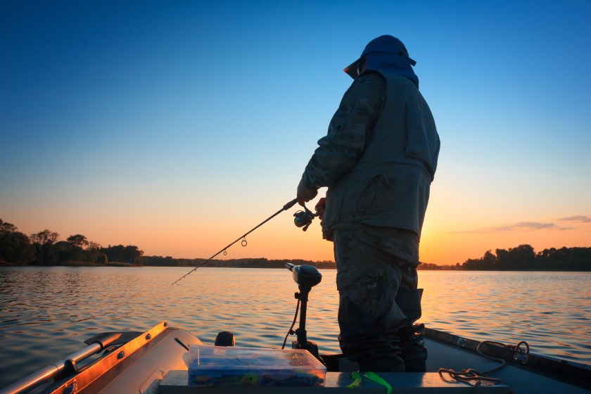 A fisherman fishing in a lake at sunset, maybe for bass